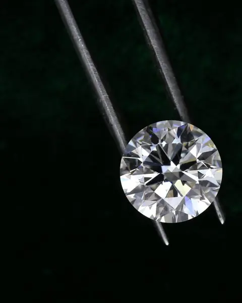 A round diamond held in tweezers